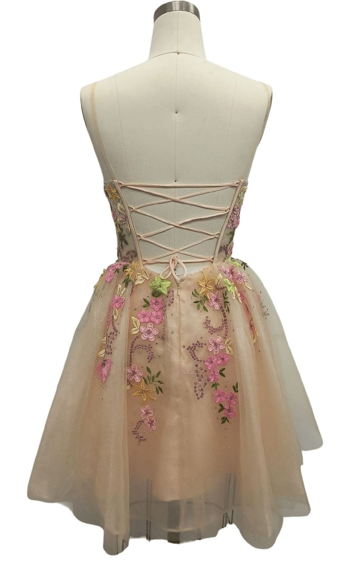 A mannequin showcases the Beaded Short Nude Hoco Dress: 12485, featuring floral embroidery, a lace-up back, and a flared tulle skirt.